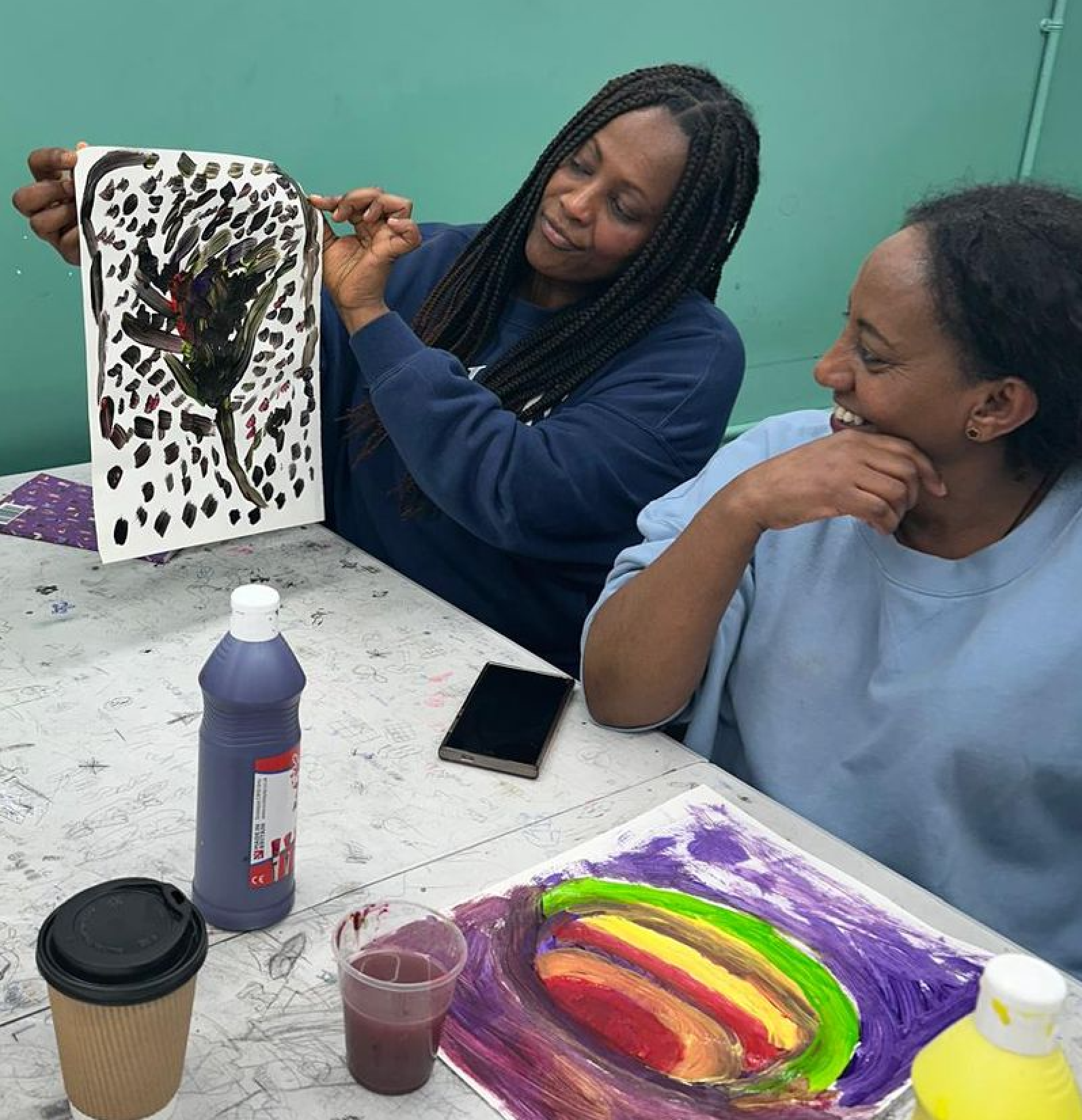 Two participants sharing their paintings at a wellbeing through art workshop