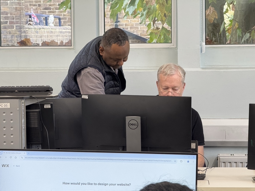A trainer supporting a learner at a computer during a digital skills session